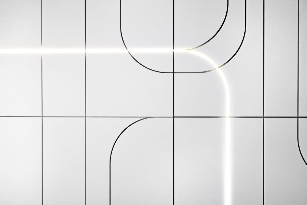 Frameless Custom Cut Nahaufnahme eines weißen Akustikpaneels mit gefrästen Rundungen und leuchtender LED-Lichtlinie im Fräsmuster