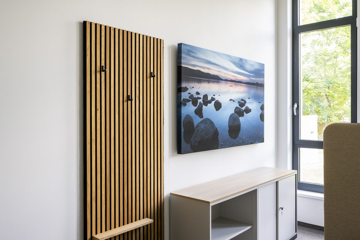 Frameless Picture rahmenloses Akustikbild mit bedrucktem Motiv eines Sees mit Steinen als Schallschutz neben einer Holzlamellenwand