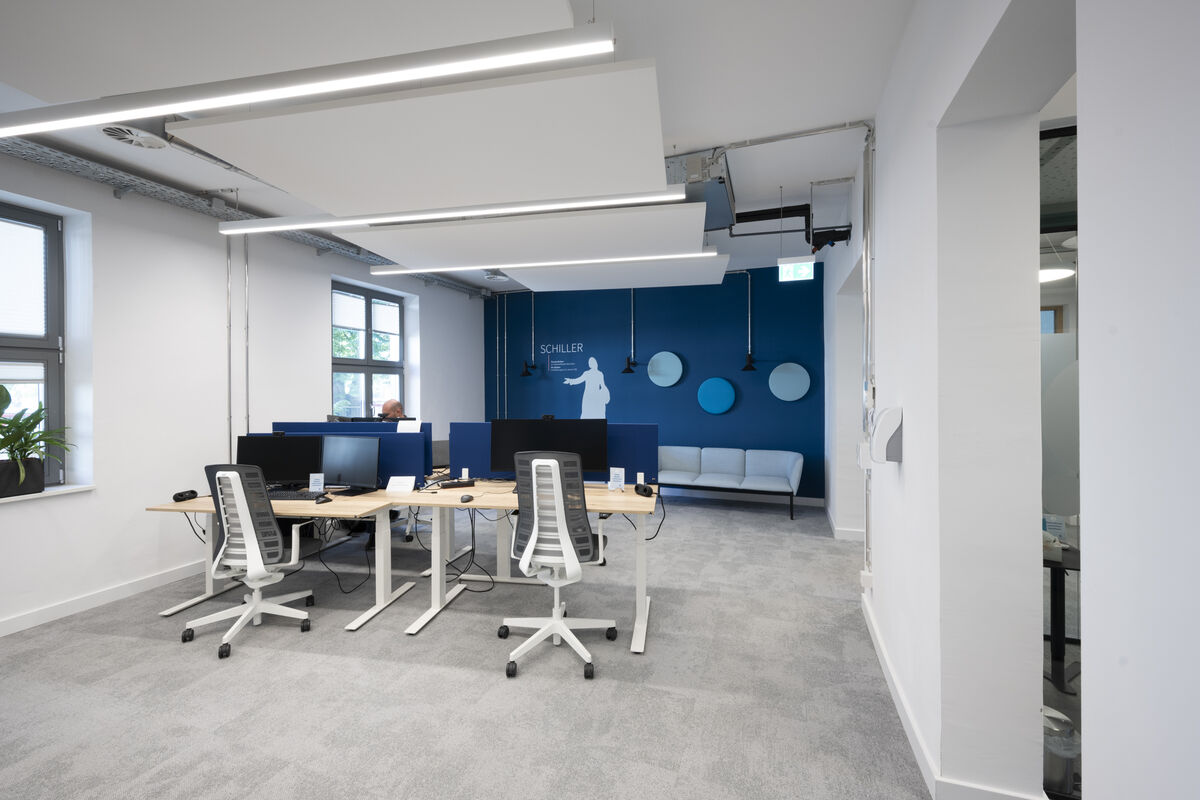 Frameless Sky weißes Akustik-Deckensegel als Schallabsorber über einer Lounge-Sitzecke mit blauer Wandgestaltung
