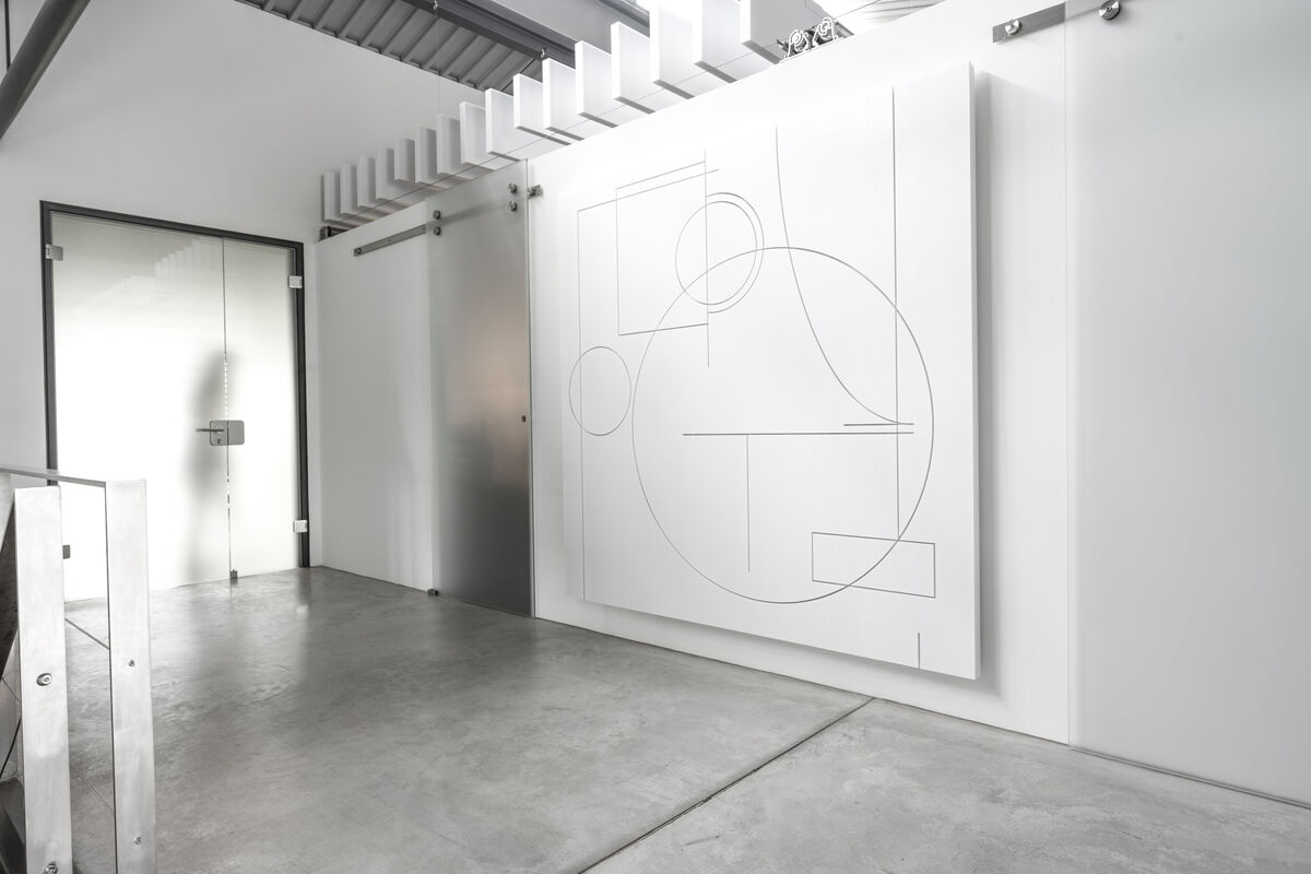 Frameless Custom Cut großes weißes Akustikpaneel mit geometrischem Linien-Fräsmuster als Schallschutz über einem Treppengeländer