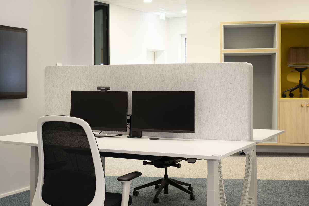 Frameless Table graue rahmenlose Akustik-Tischtrennwände als Schallschutz hinter iMac am Schreibtisch vor Fensterfront mit Bäumen
