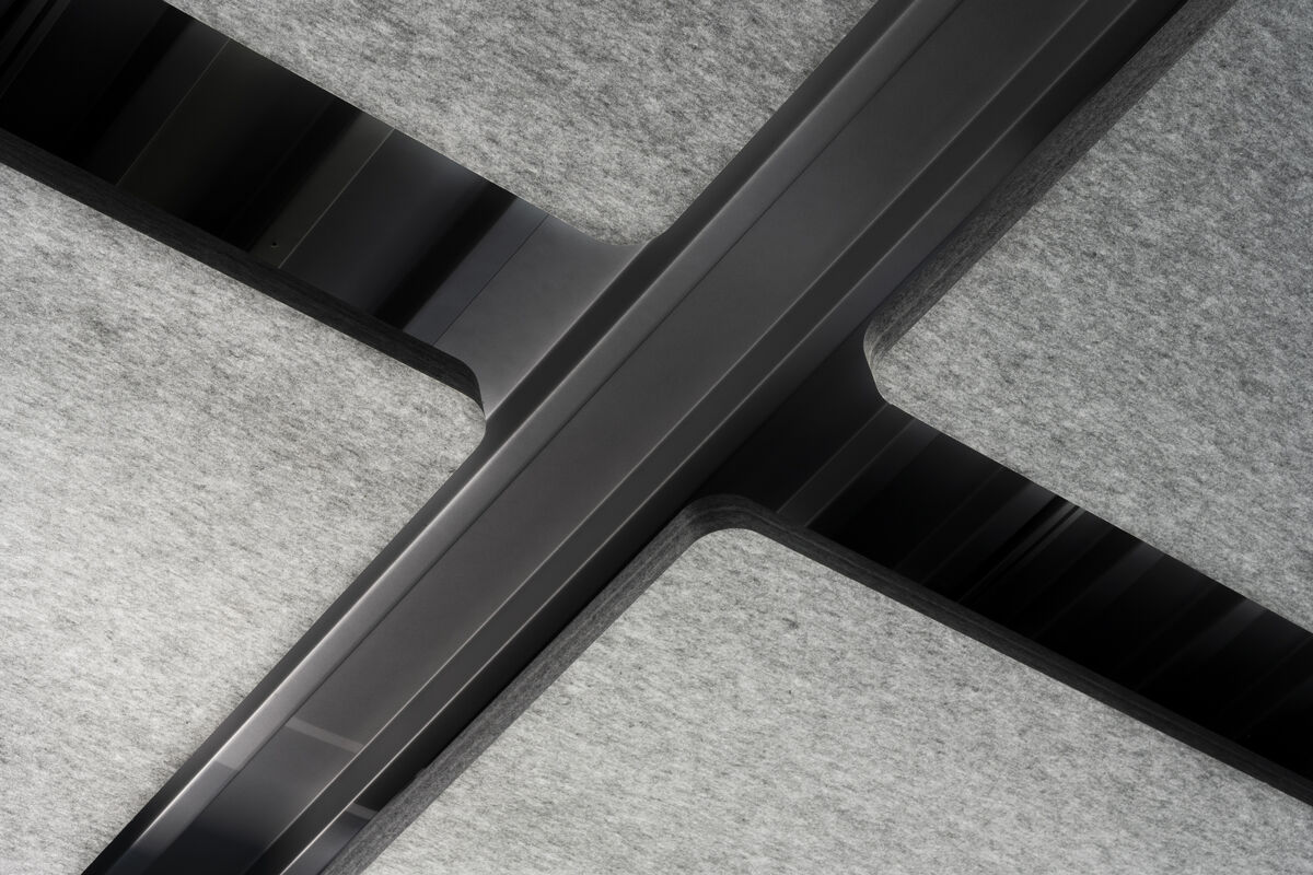 Frameless Sky Detailaufnahme eines schwarzen Aufhängungskreuzes zwischen grauen Akustik-Deckensegeln