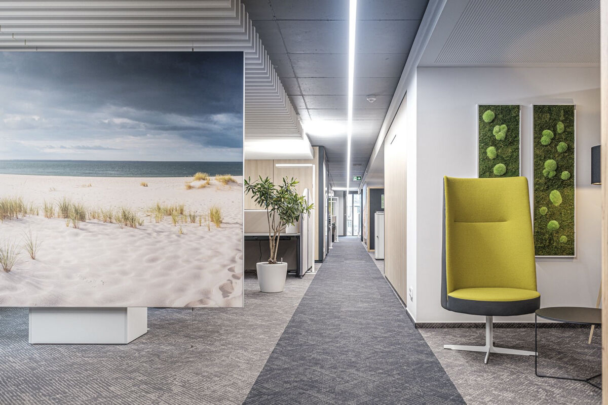 Alu Line Sky vertikal abgehängtes Akustikpaneel mit bedrucktem Strandmotiv als Raumteiler und Schallschutz im Büroflur