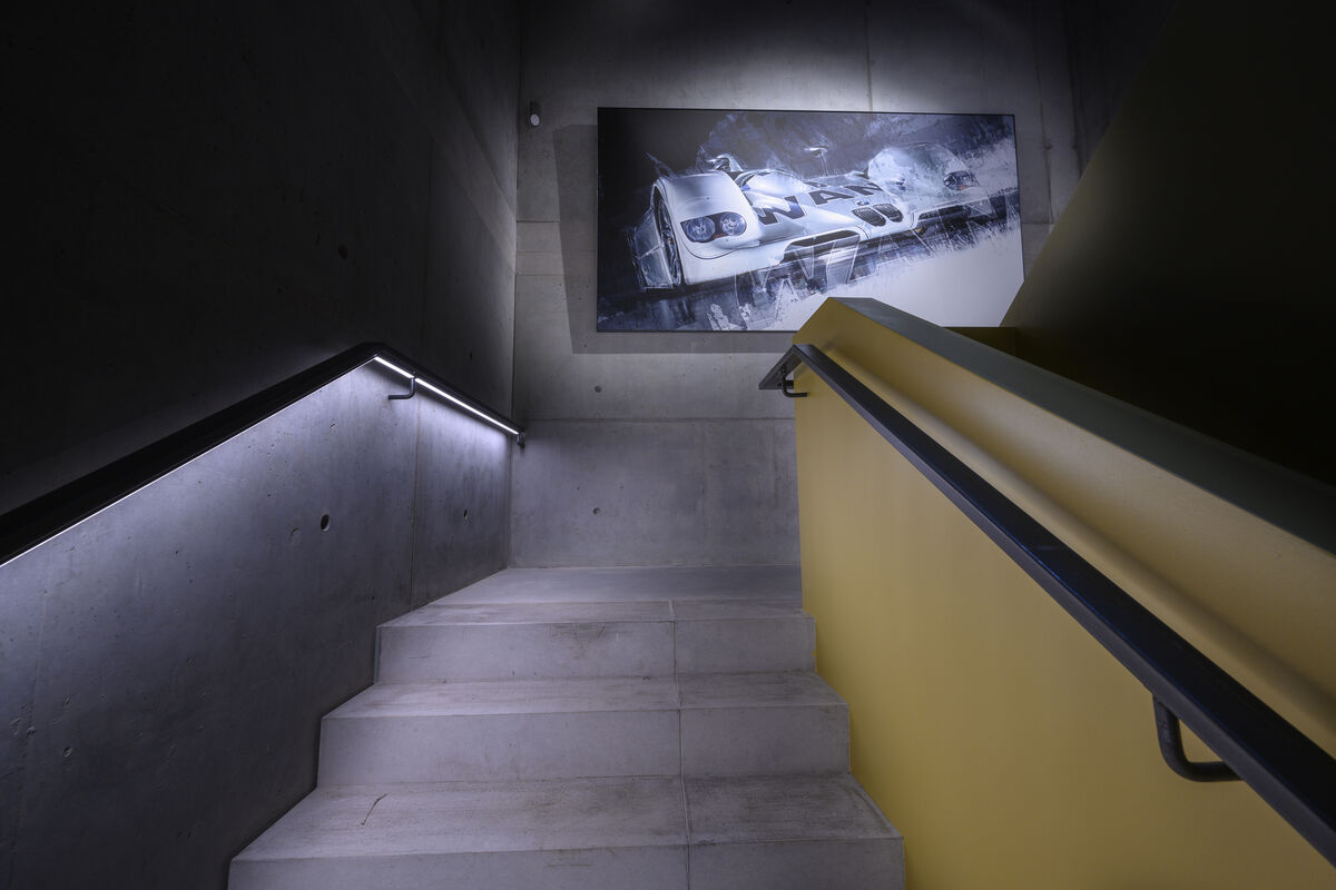 Alu Line Wall beleuchtetes Akustikbild mit bedrucktem Rennsport-Motiv als Schallschutz über einer Betontreppe