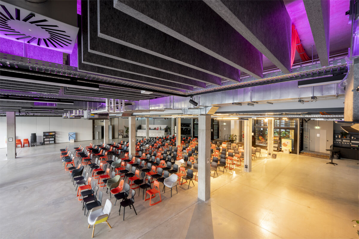 Frameless Baffle dunkle abgehängte Akustik-Baffles mit violettem Farblicht als Schallschutz in einer bestuhlten Eventhalle